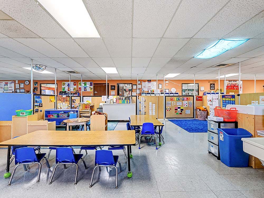 Empty children's classroom with small tables and chairs