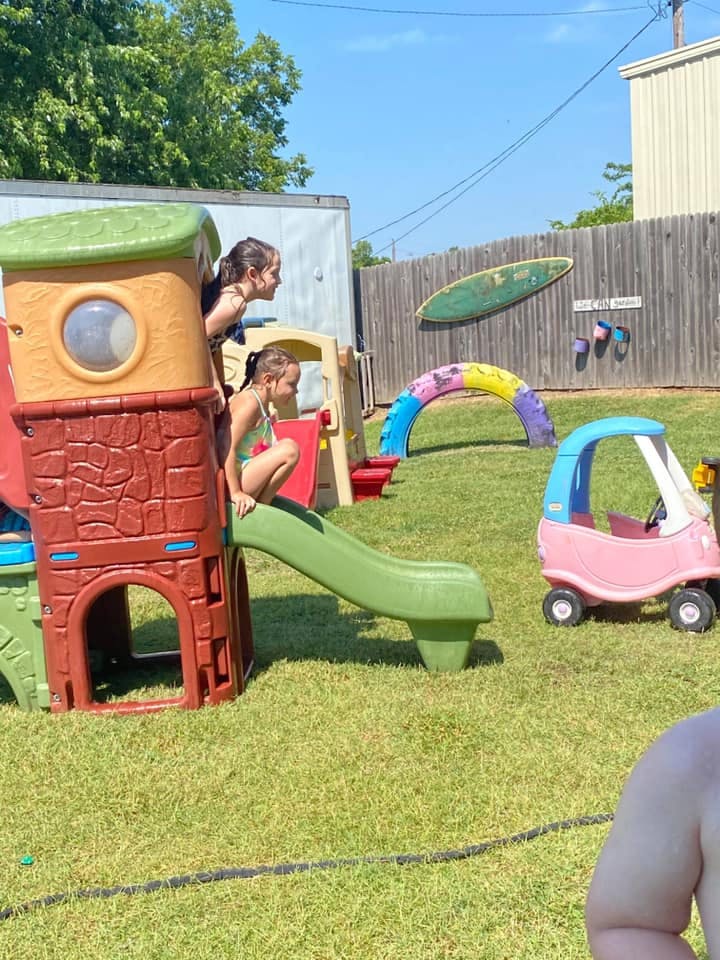 Two children on a playground slide and play structure