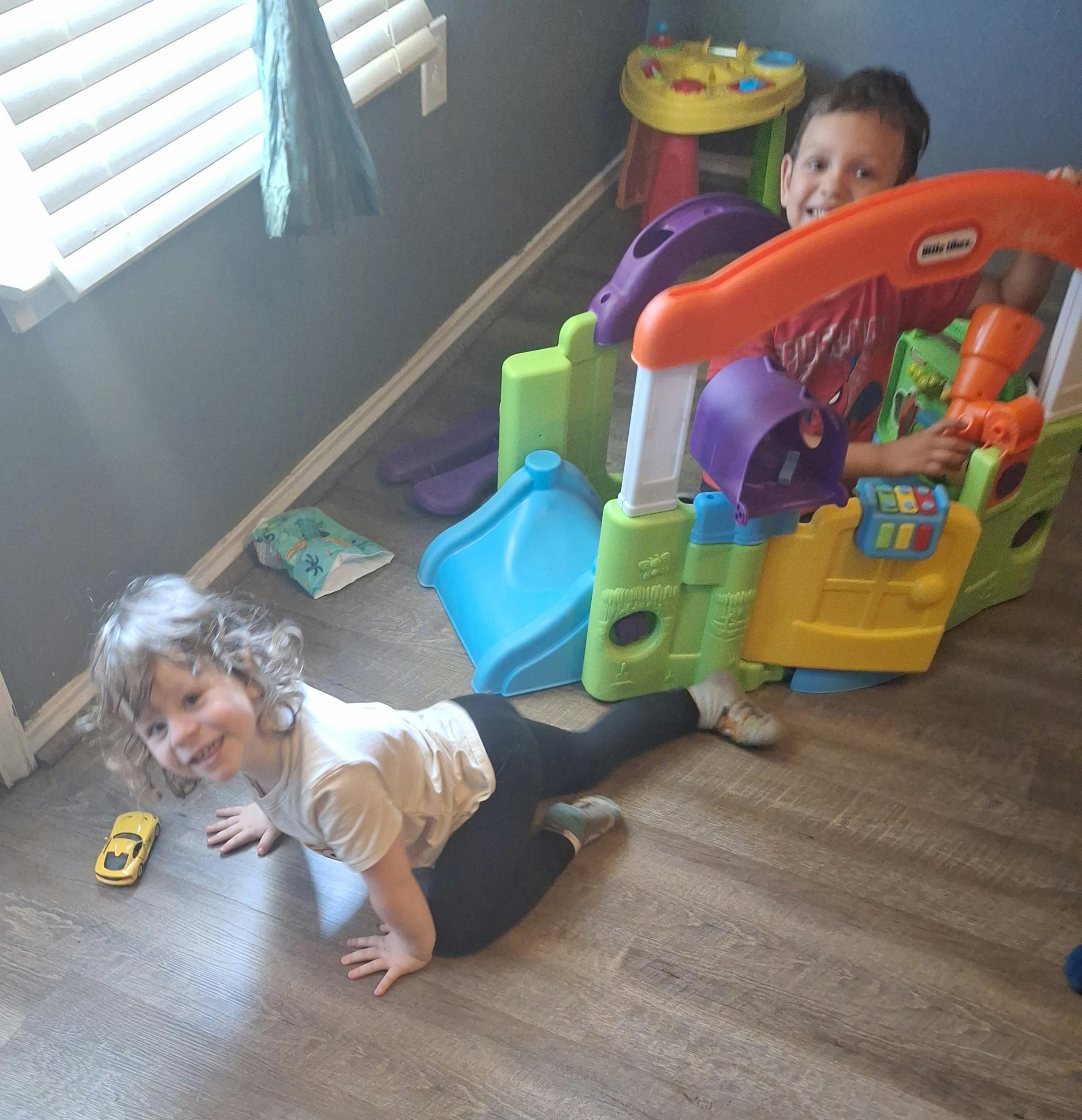 Two children playing with a colorful toy structure indoors