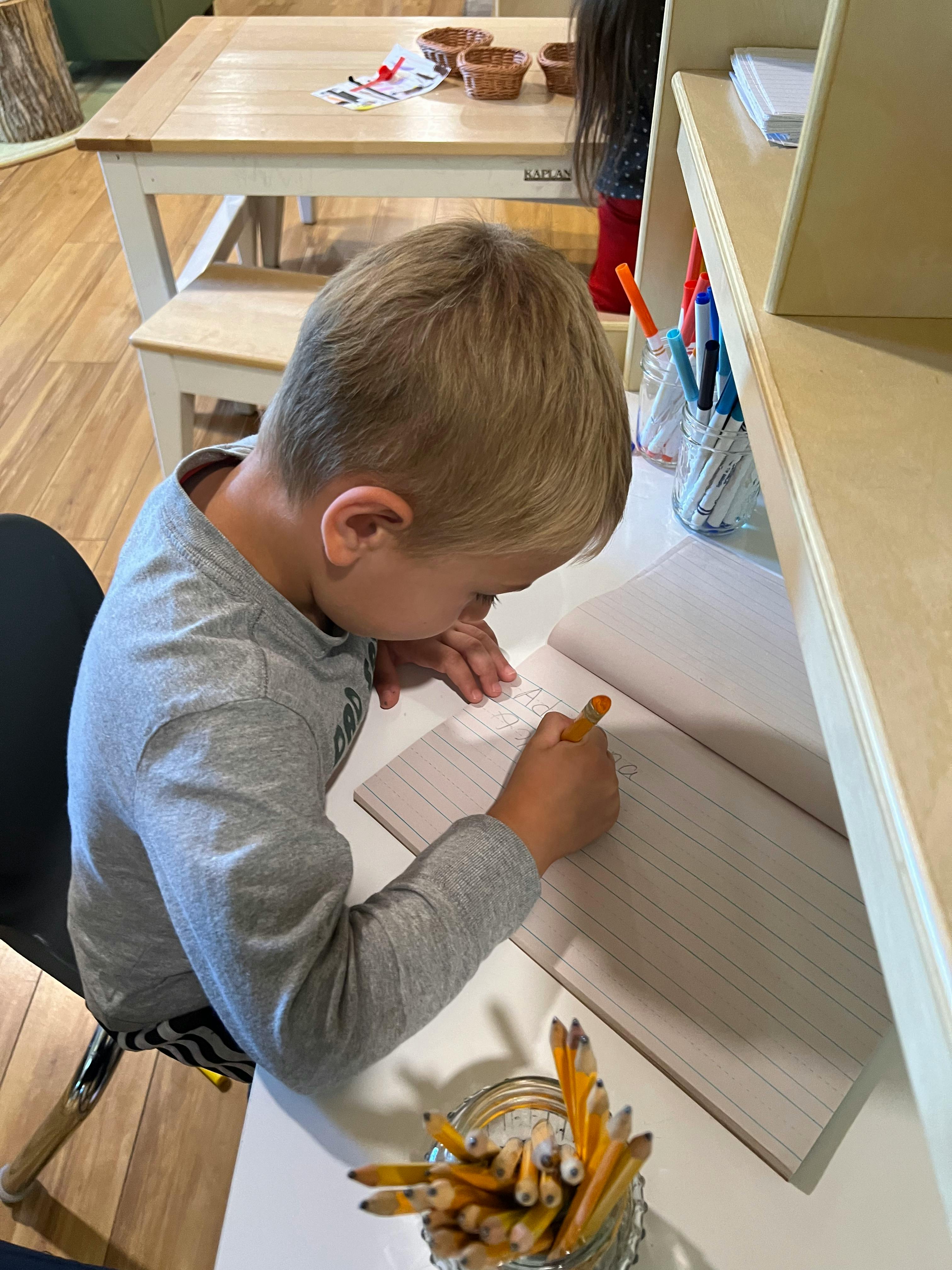 Child writing in a notebook at a desk