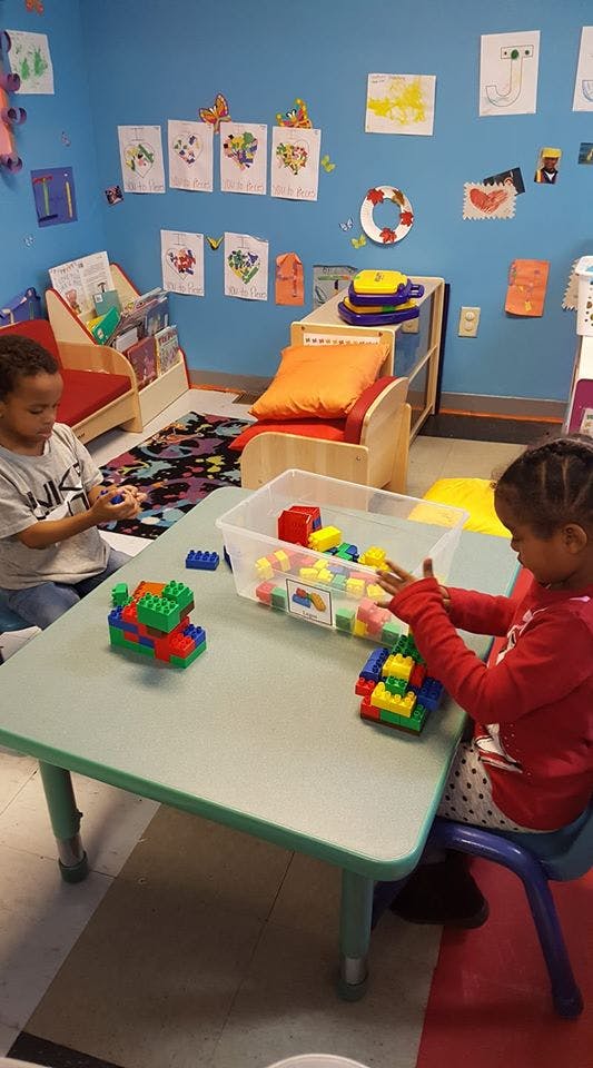 Two children playing with colorful building blocks at a table