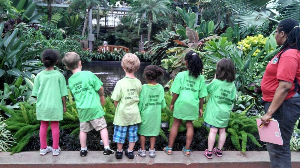 Children and an adult looking at plants in a garden