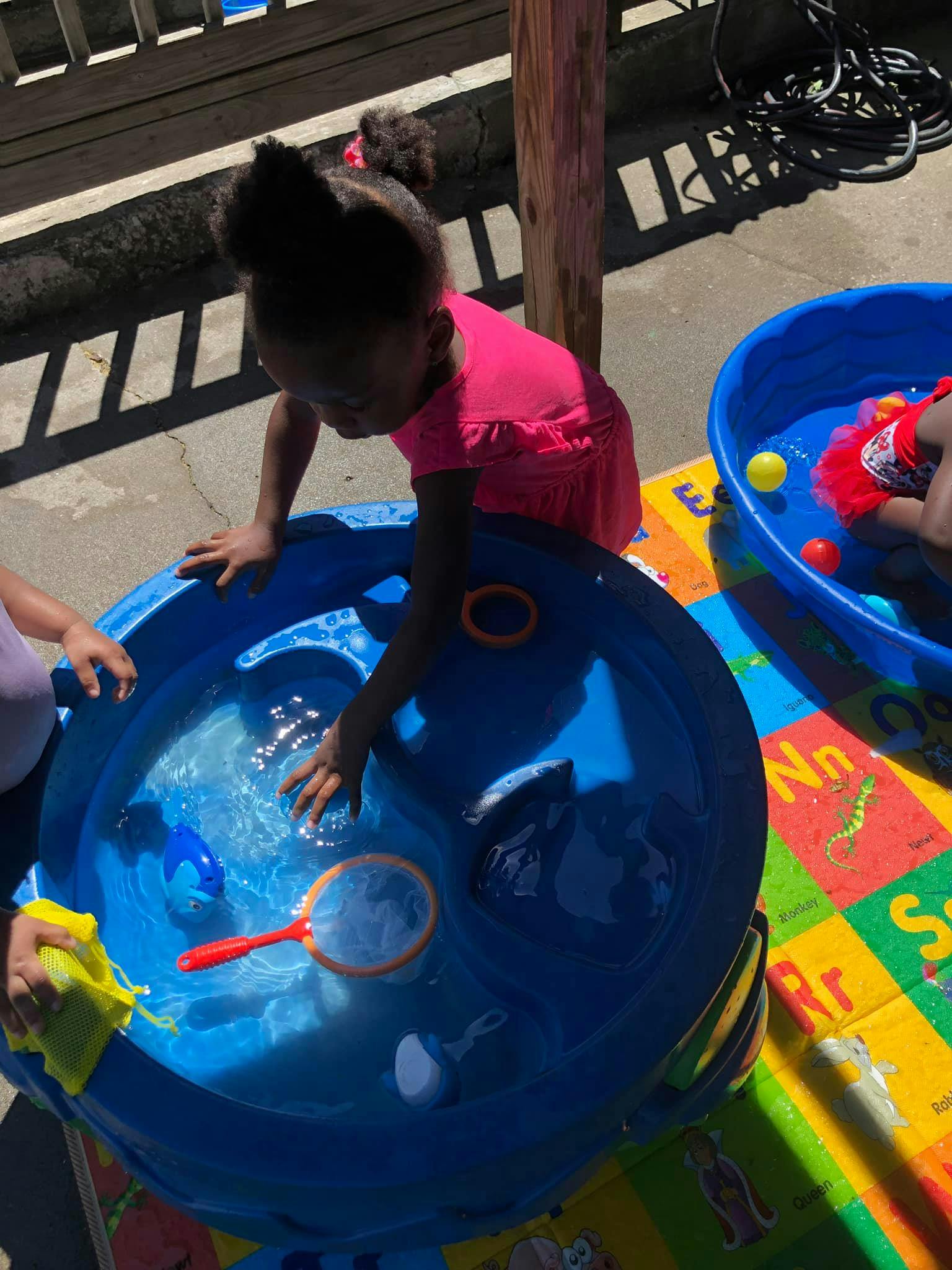 Child playing with water in a blue basin