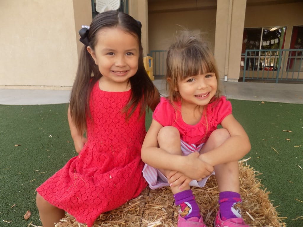 Two children sitting on a hay bale
