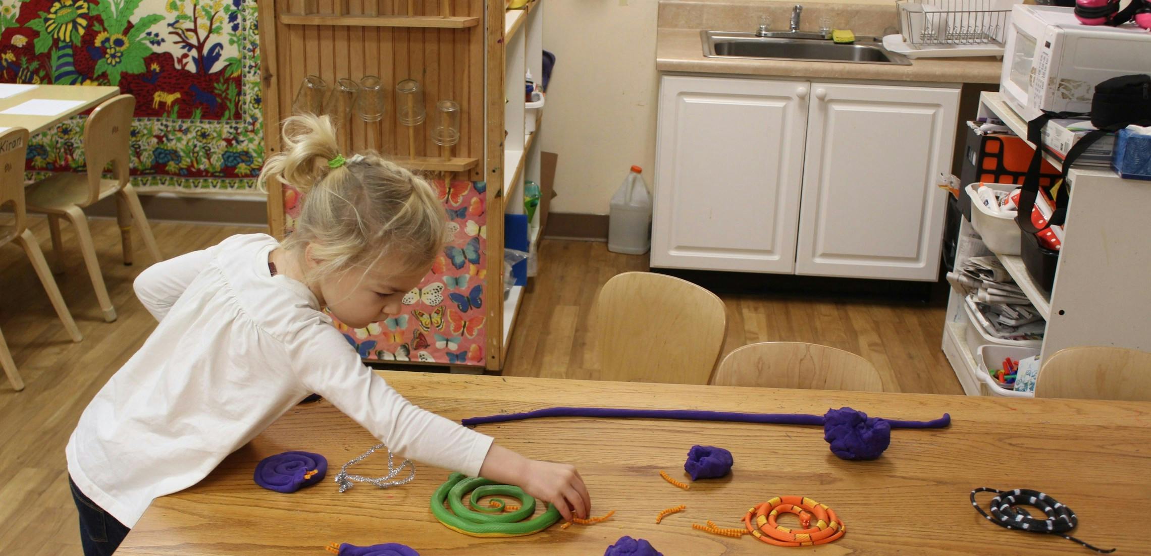 Child playing with colorful objects on a wooden table