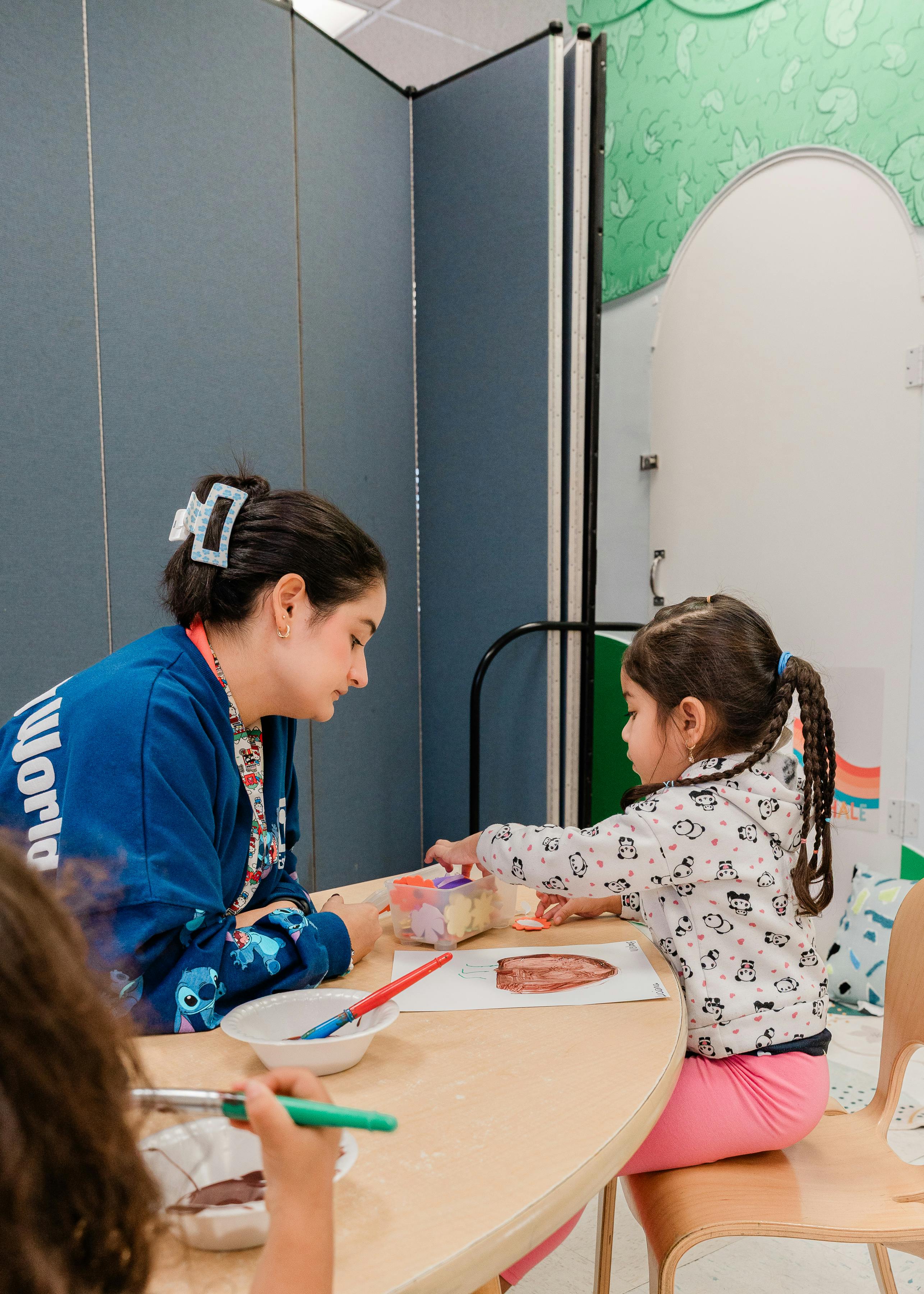 Adult and child painting at a table in a classroom