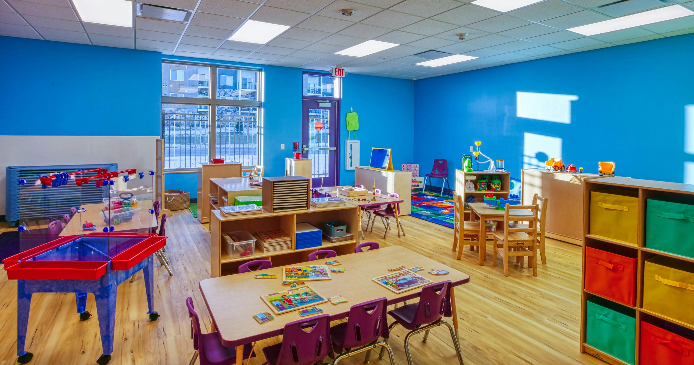 Empty colorful children's classroom with tables, chairs, and toys