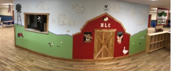 Wall mural with a red barn, green hills, and farm animal cutouts