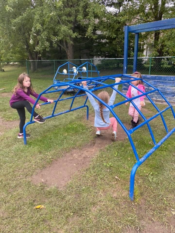 Three children playing on a blue climbing structure on a playground