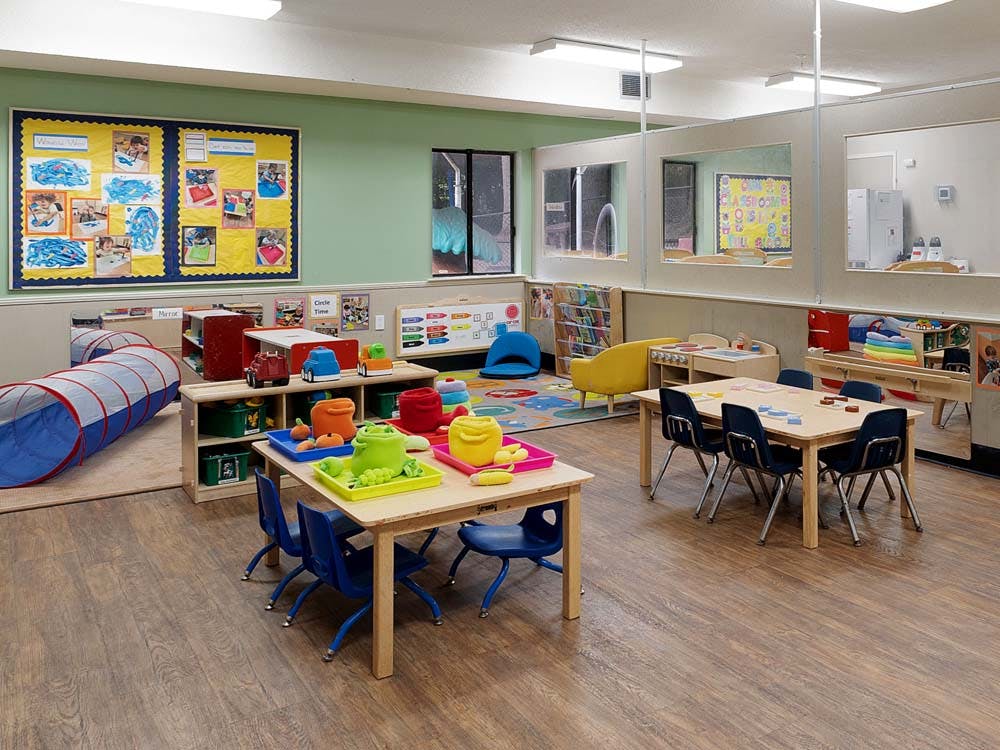 Playroom with tables, chairs, tunnel, and shelves of toys
