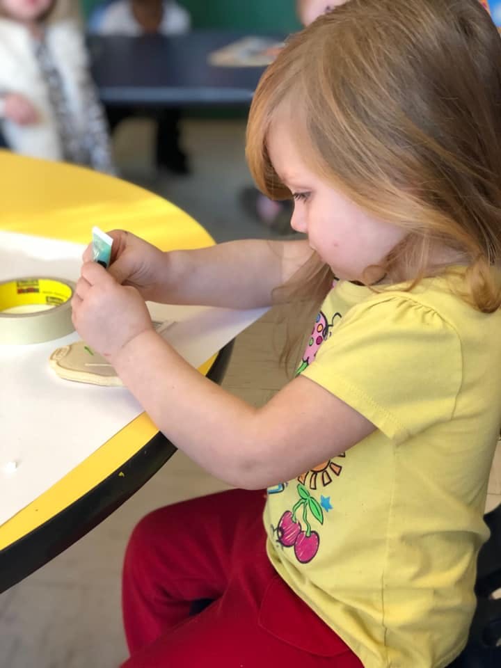 Child applying glue to a craft project at a table