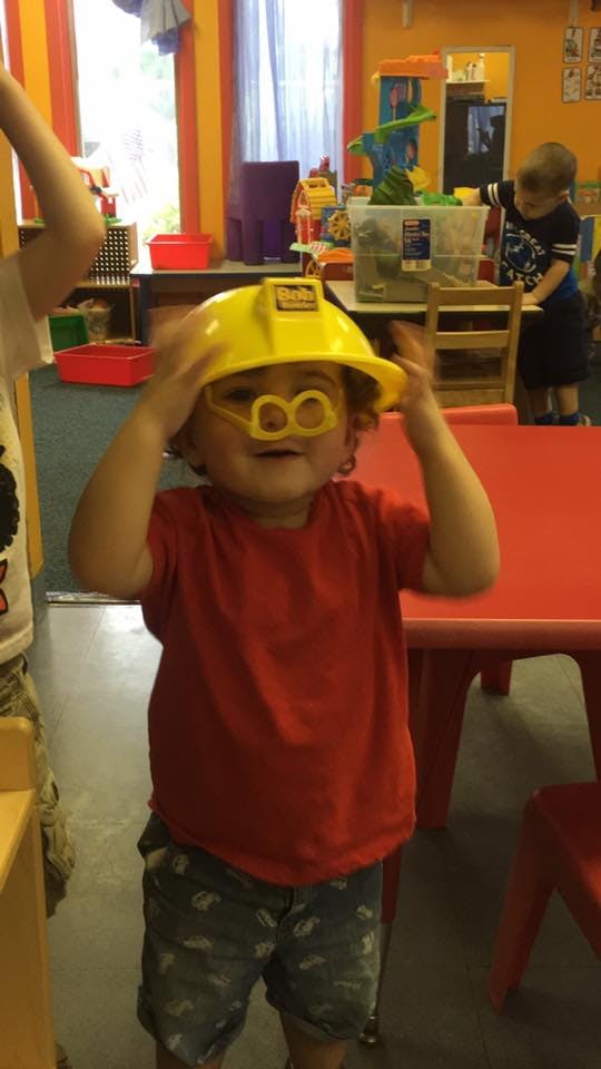 Child wearing a yellow construction hat and yellow novelty glasses