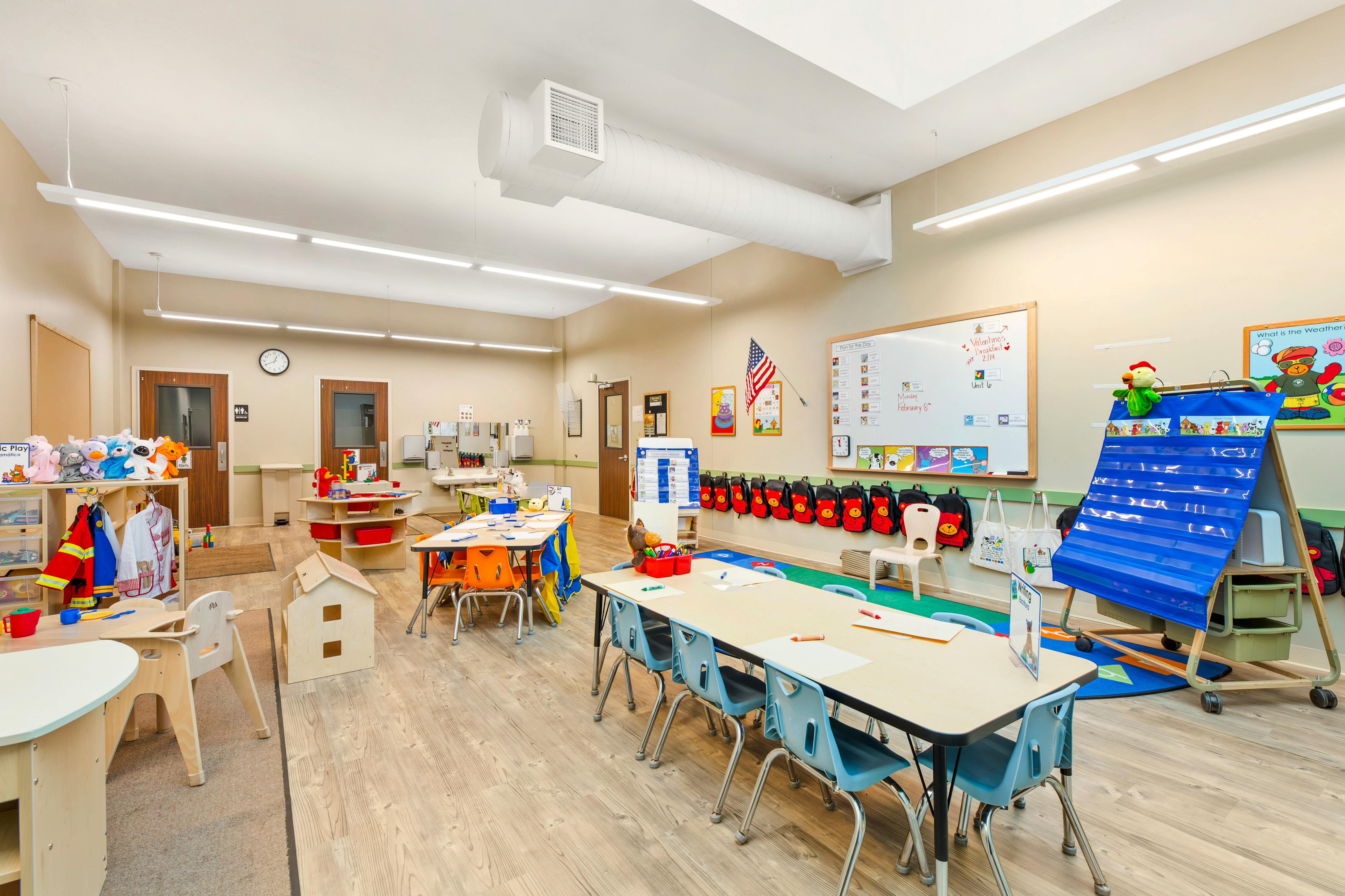 An empty early childhood classroom with multiple small tables and chairs