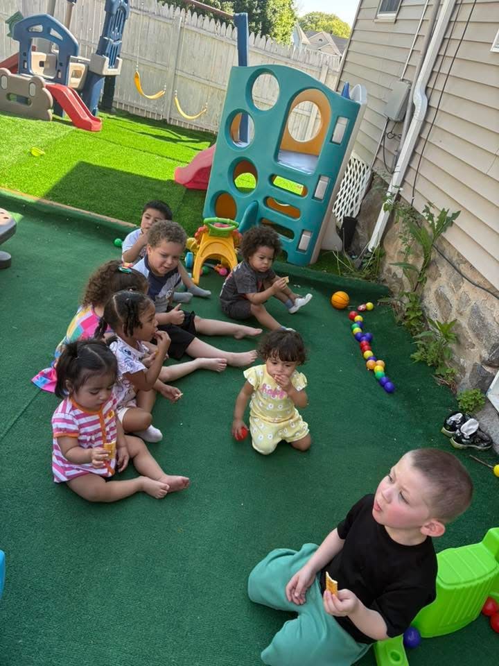 Group of children sitting on a turf playground eating snacks
