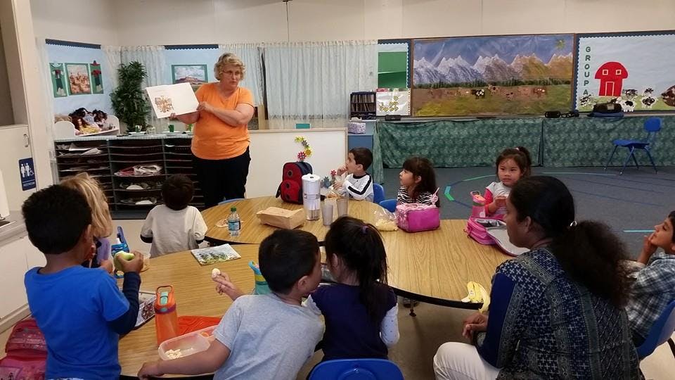 Adult reading a book to children in a classroom