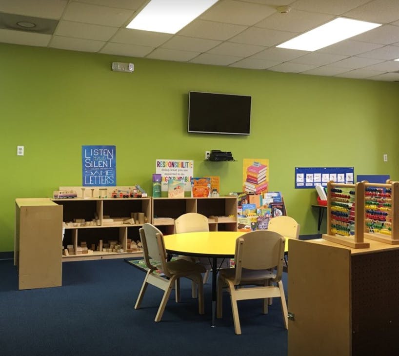 Classroom with small yellow table and chairs, shelves, and abacus