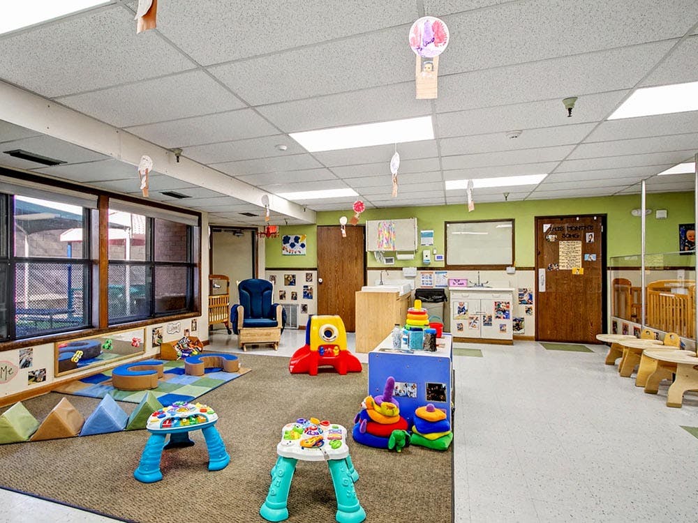 Playroom with bright toys, soft blocks, and cribs