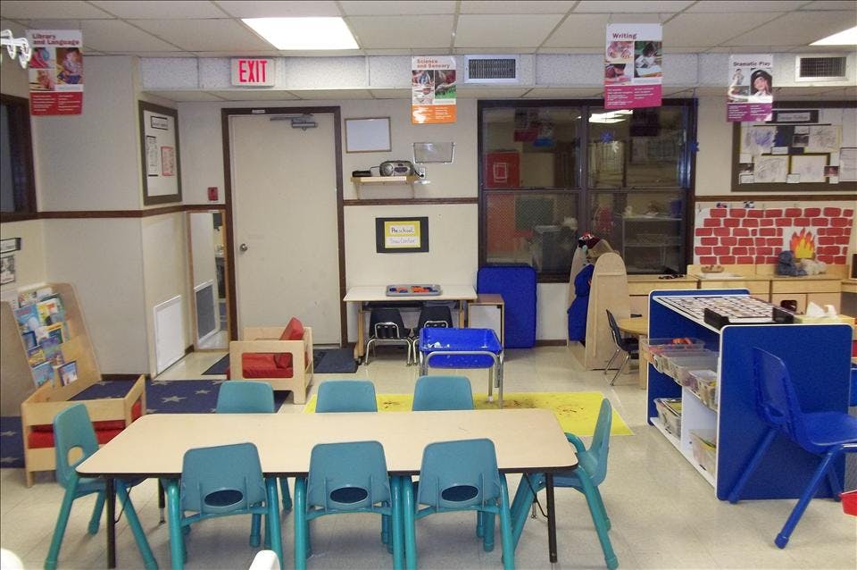 Classroom with small tables and chairs, an exit sign, and learning banners