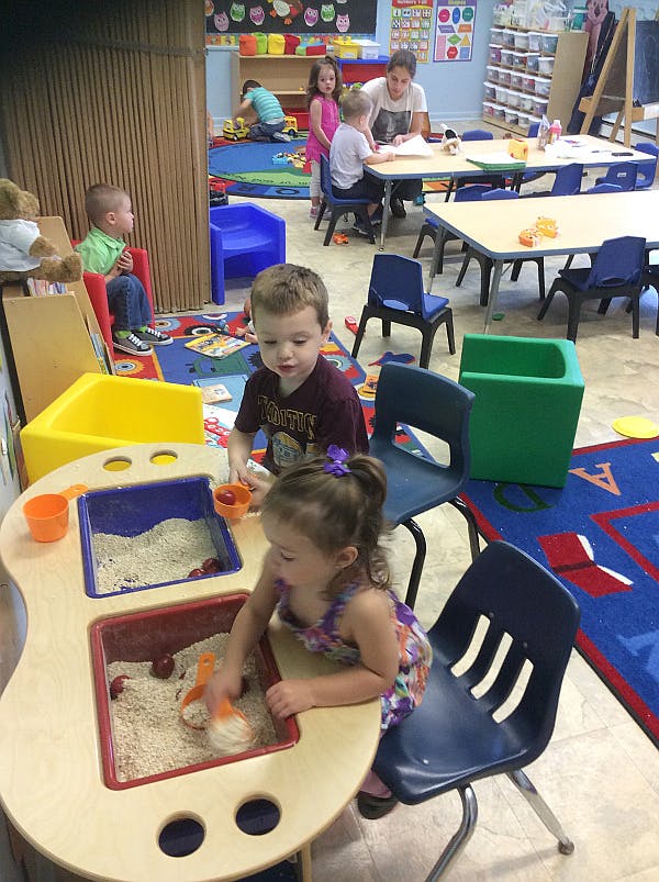 Children playing in a classroom with sand and toys