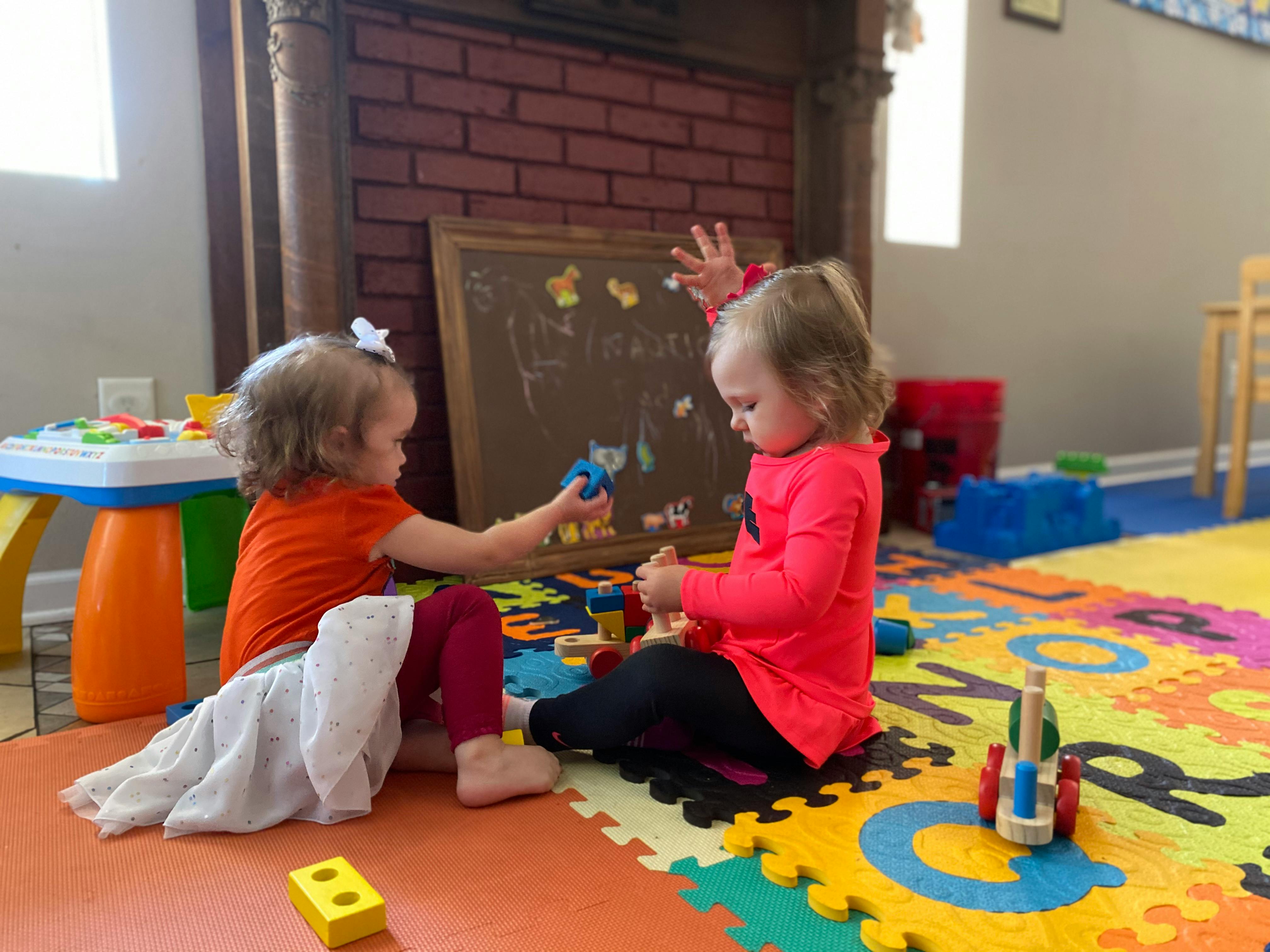Two children playing with toys on a colorful alphabet mat