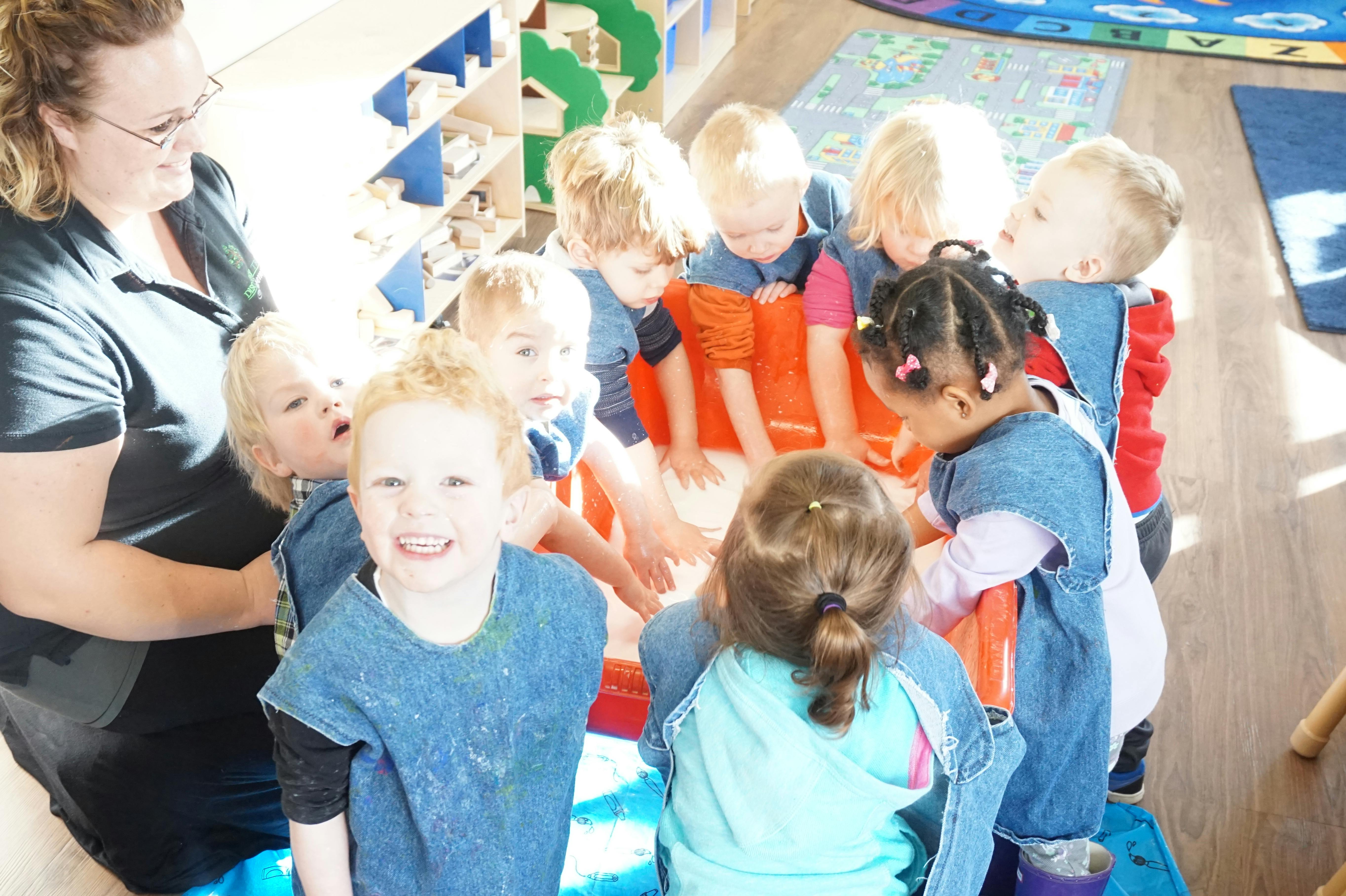 Adult and multiple children gathered around a table in a classroom