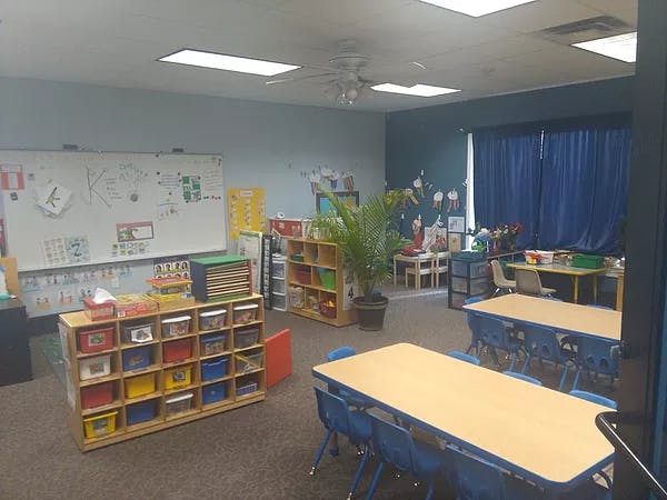 Classroom with small tables and chairs, storage units, and a whiteboard
