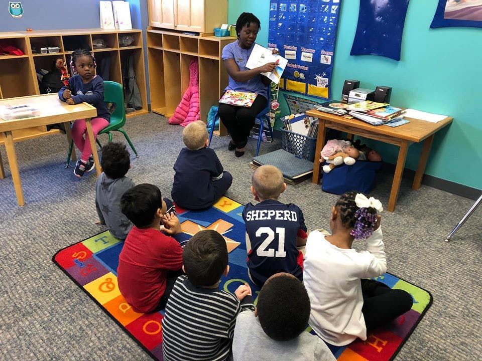 Adult reading to a group of children sitting on a colorful rug