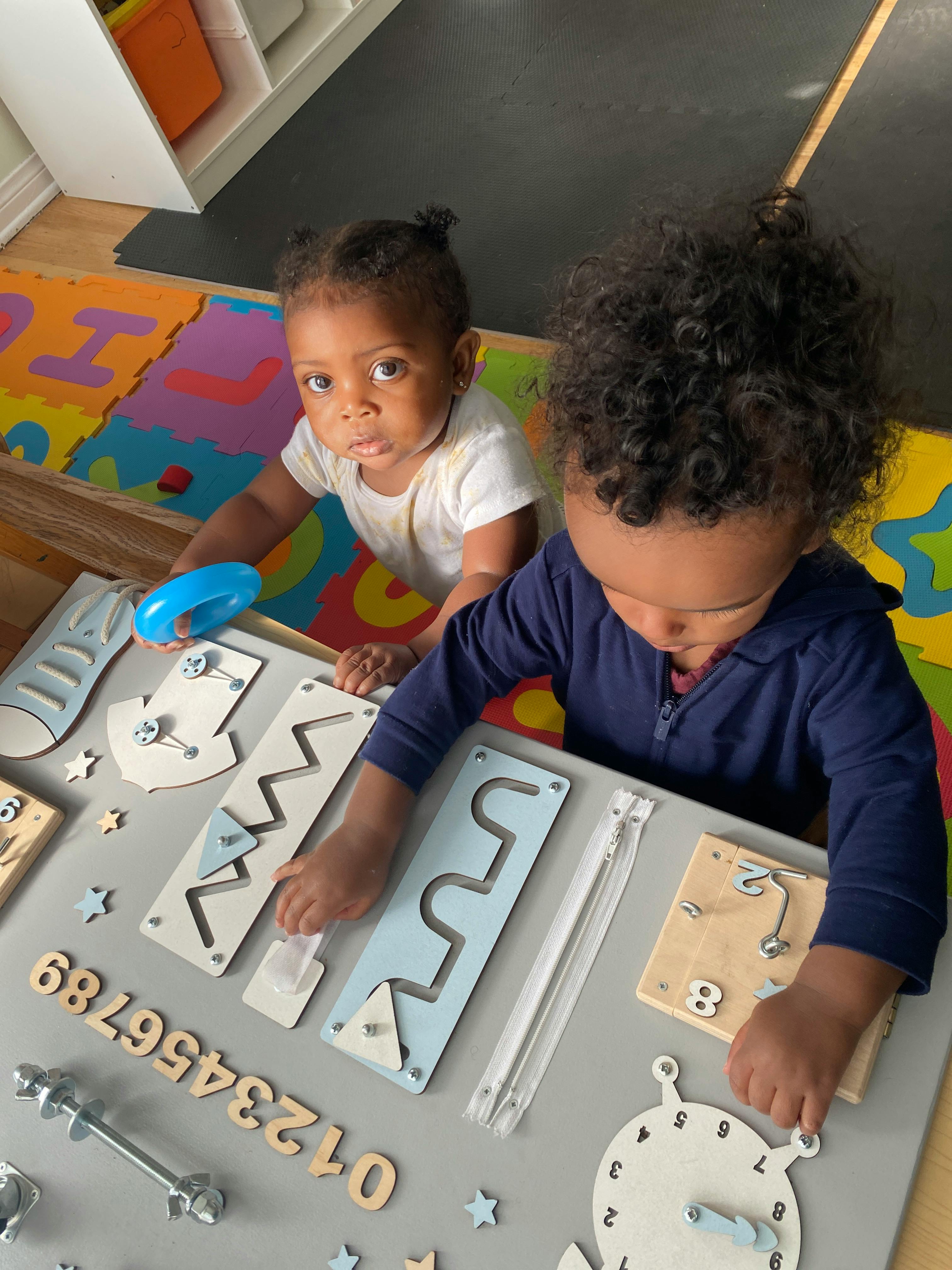 Two children playing with a busy board