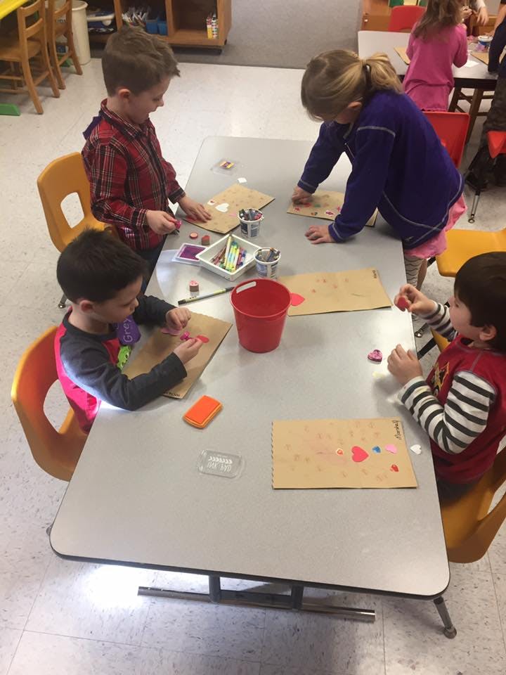 Children sitting at a table doing crafts in-class craft activities