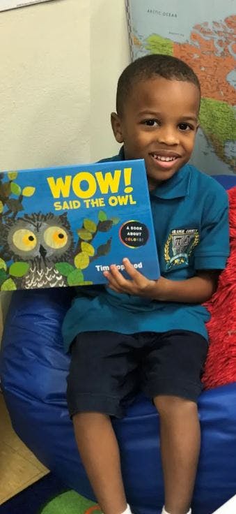 Child holding a book titled "WOW! Said the Owl"