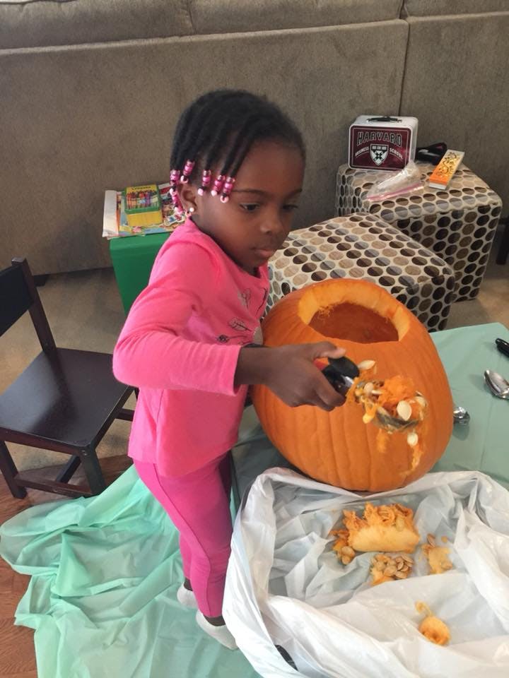 Child scooping out the inside of a pumpkin