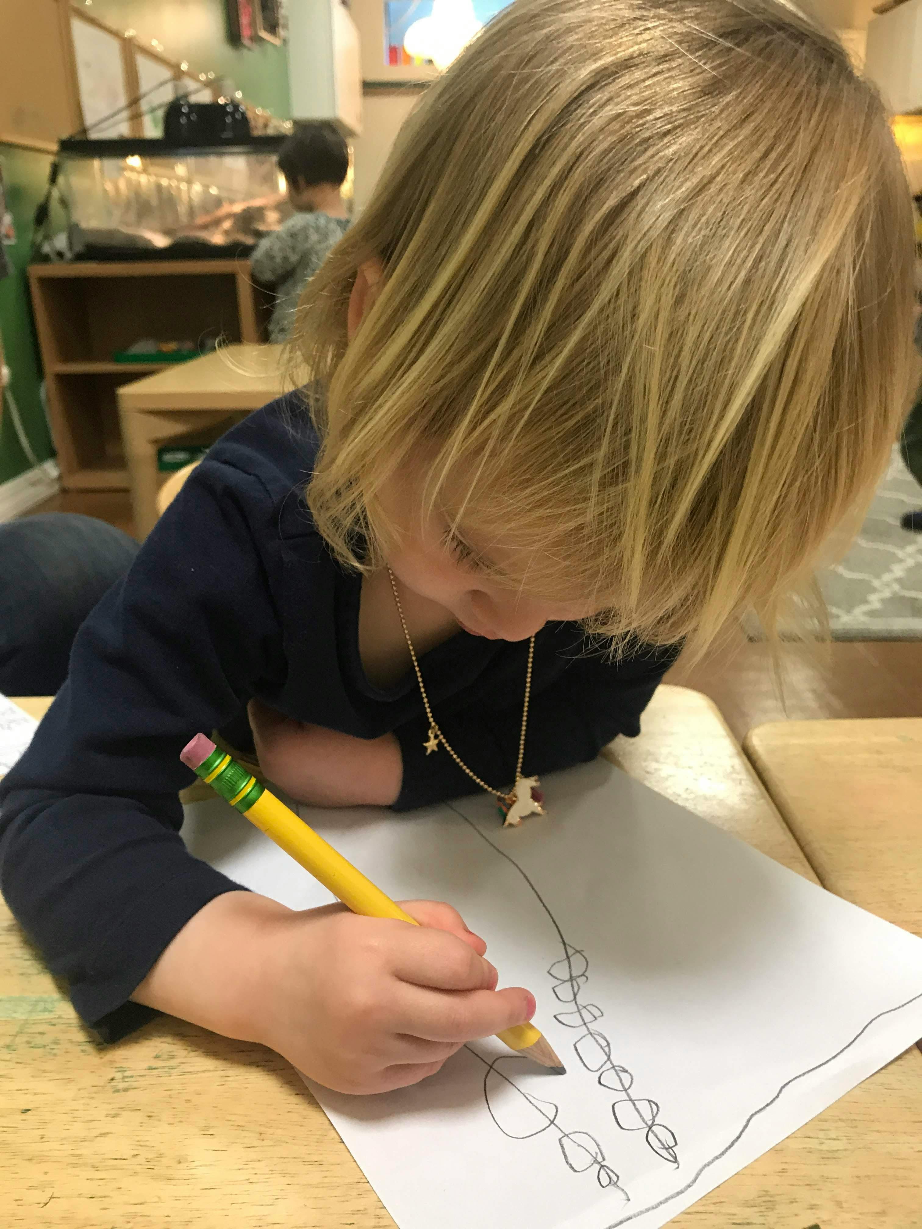 Child drawing on paper with a pencil