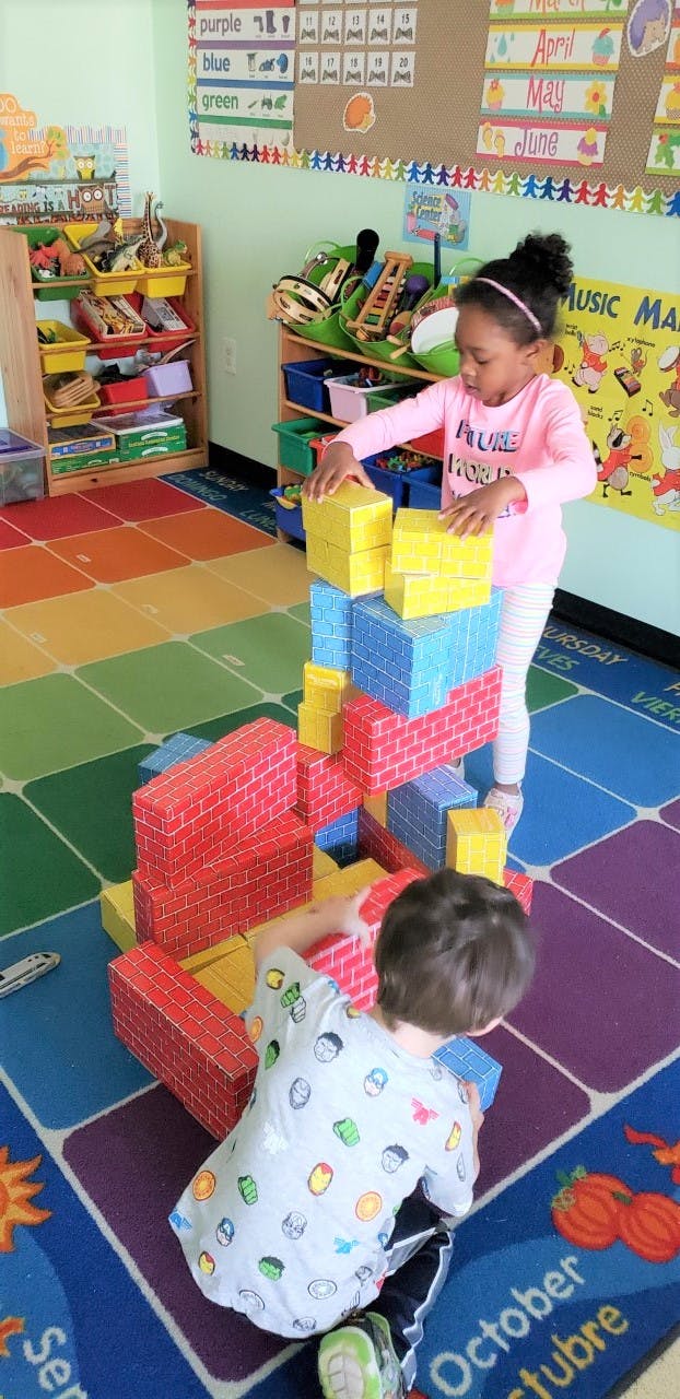 Two children playing with large building blocks in a classroom