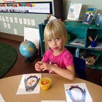 Child sitting at a table with papers and a small bowl