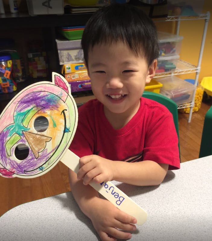 Child holding a colorful paper mask