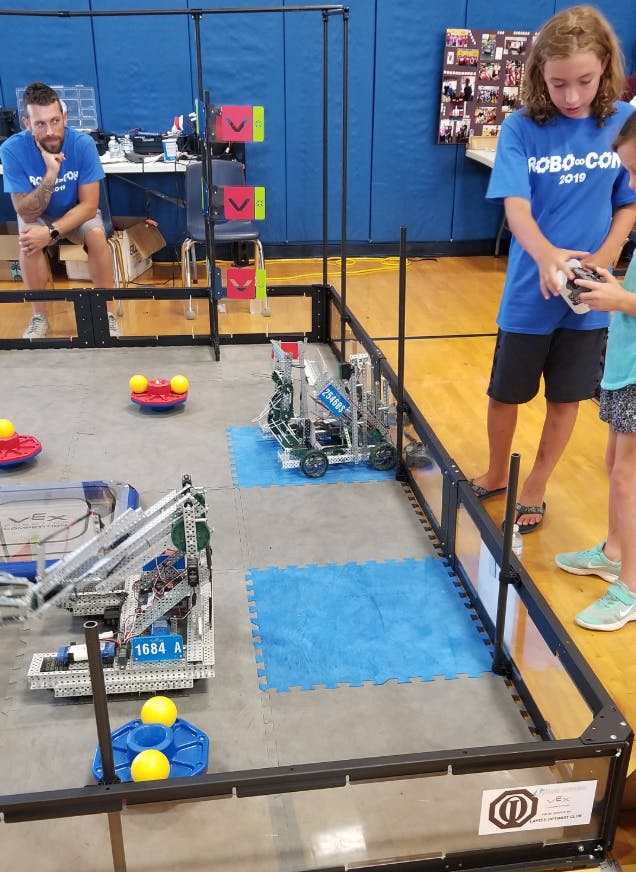 Person operating a robot with a remote control in a competition area