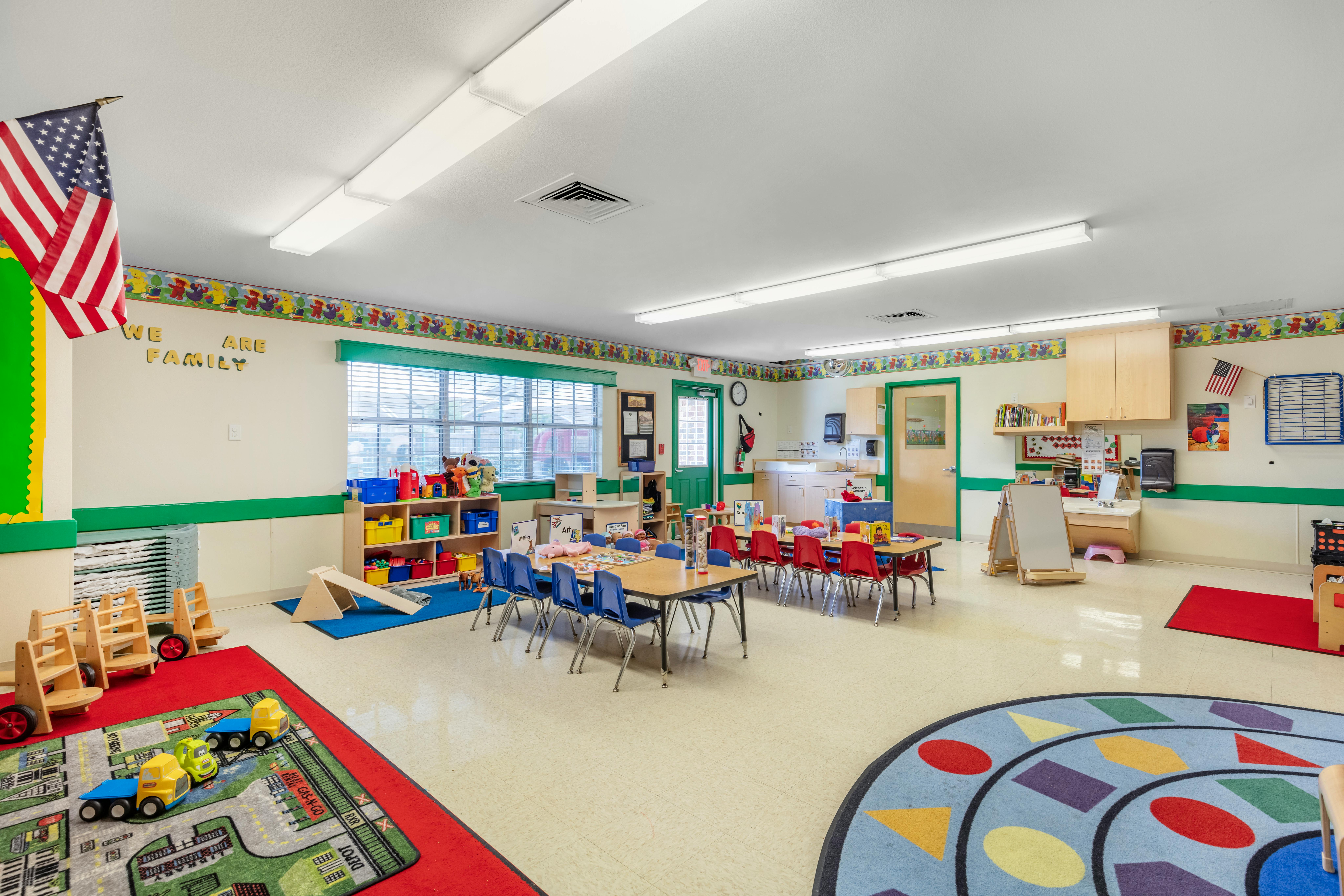 Classroom with child-sized tables and chairs, play mats, and learning materials