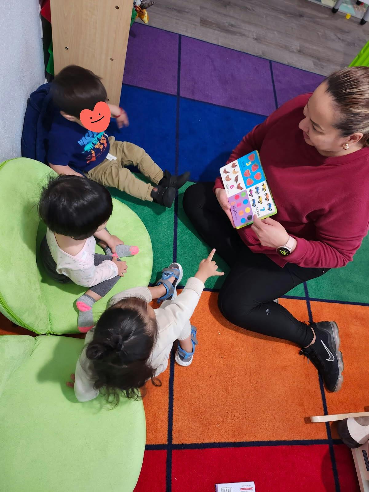 Adult holding a book with three children sitting on the floor