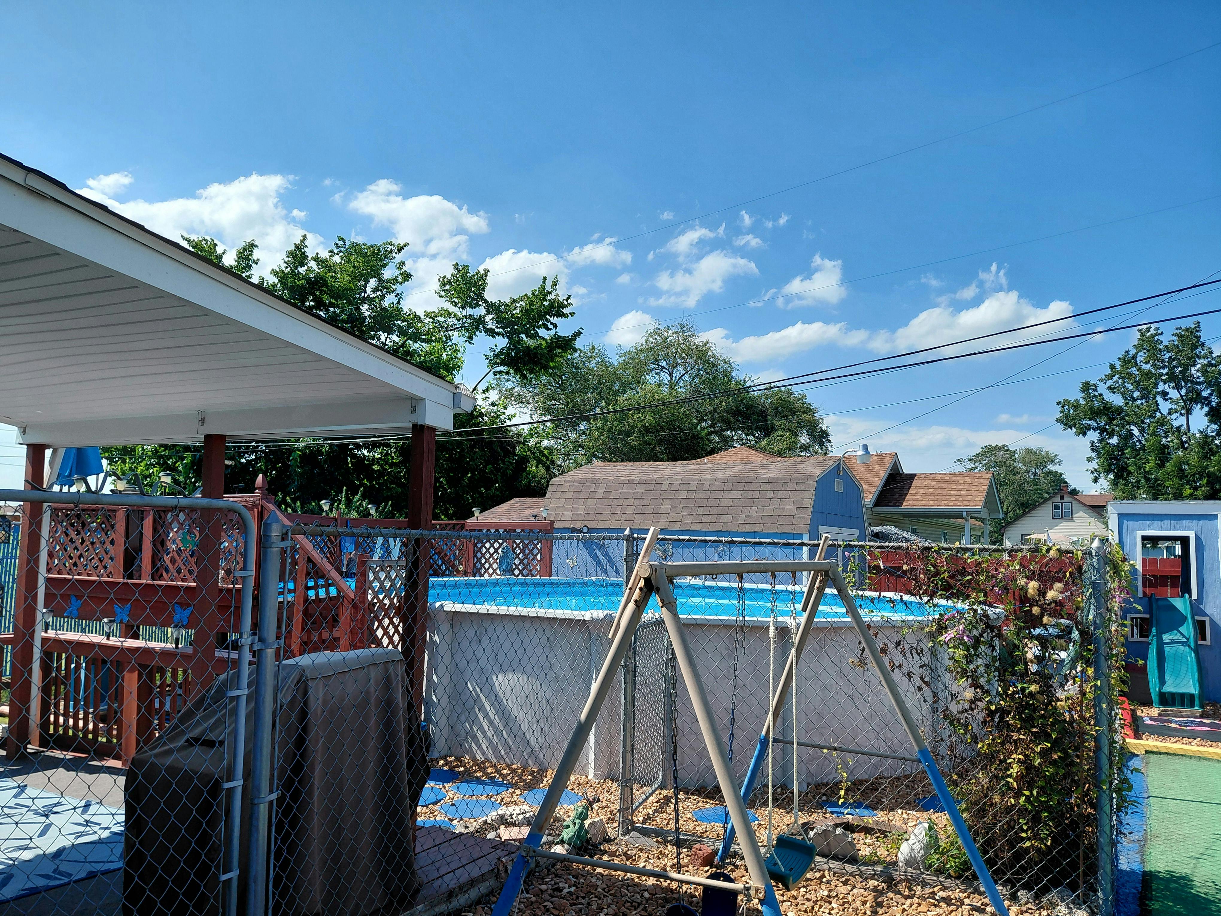 Above ground pool and swing set in a fenced backyard