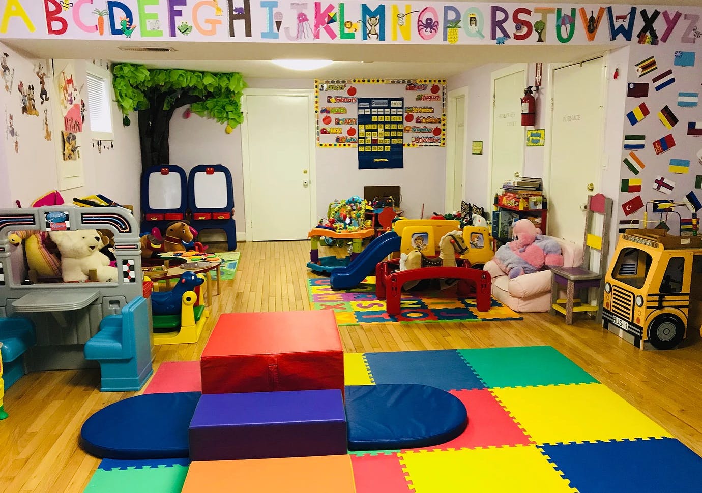 Playroom with colorful mats, toys, and alphabet banner