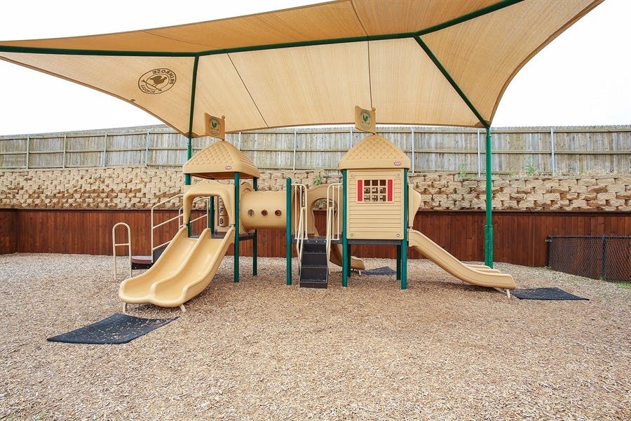 Playground with slides and climbing structure under a shade canopy