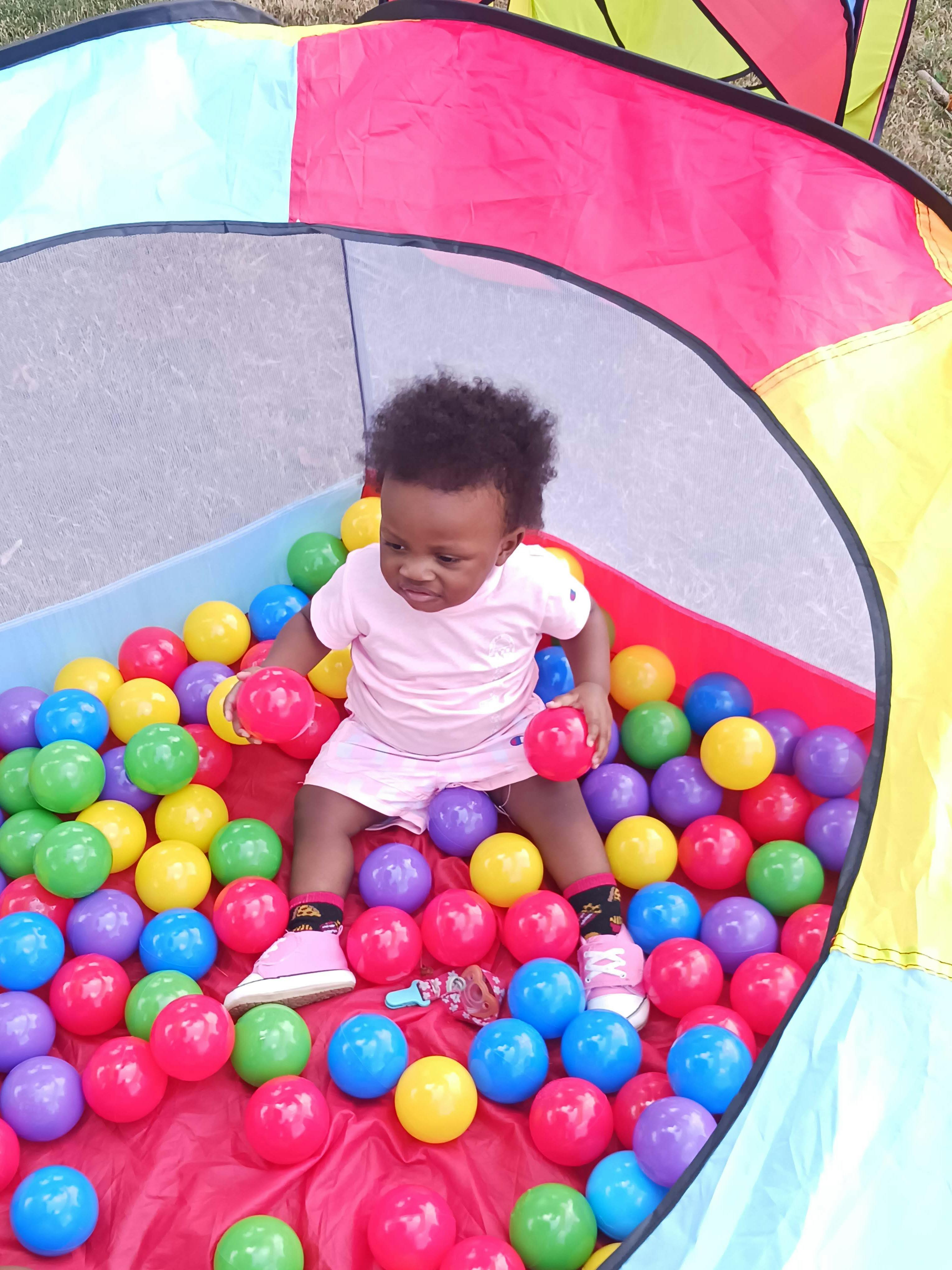 Child in a ball pit holding two balls