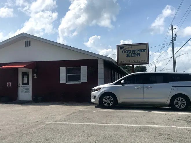 White minivan parked in front of a building with a "Country Kids" sign