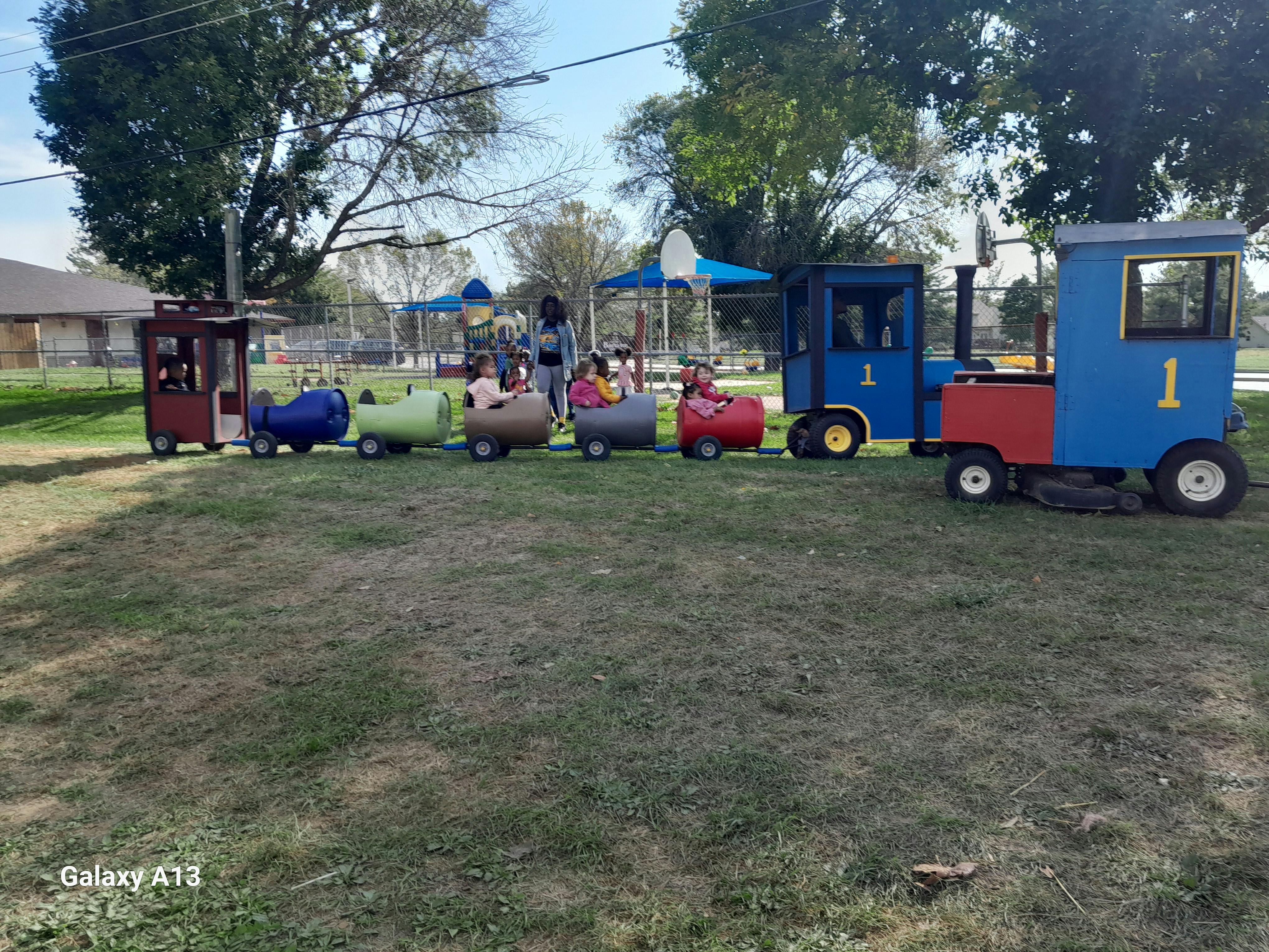 Children riding in a small train ride outdoors