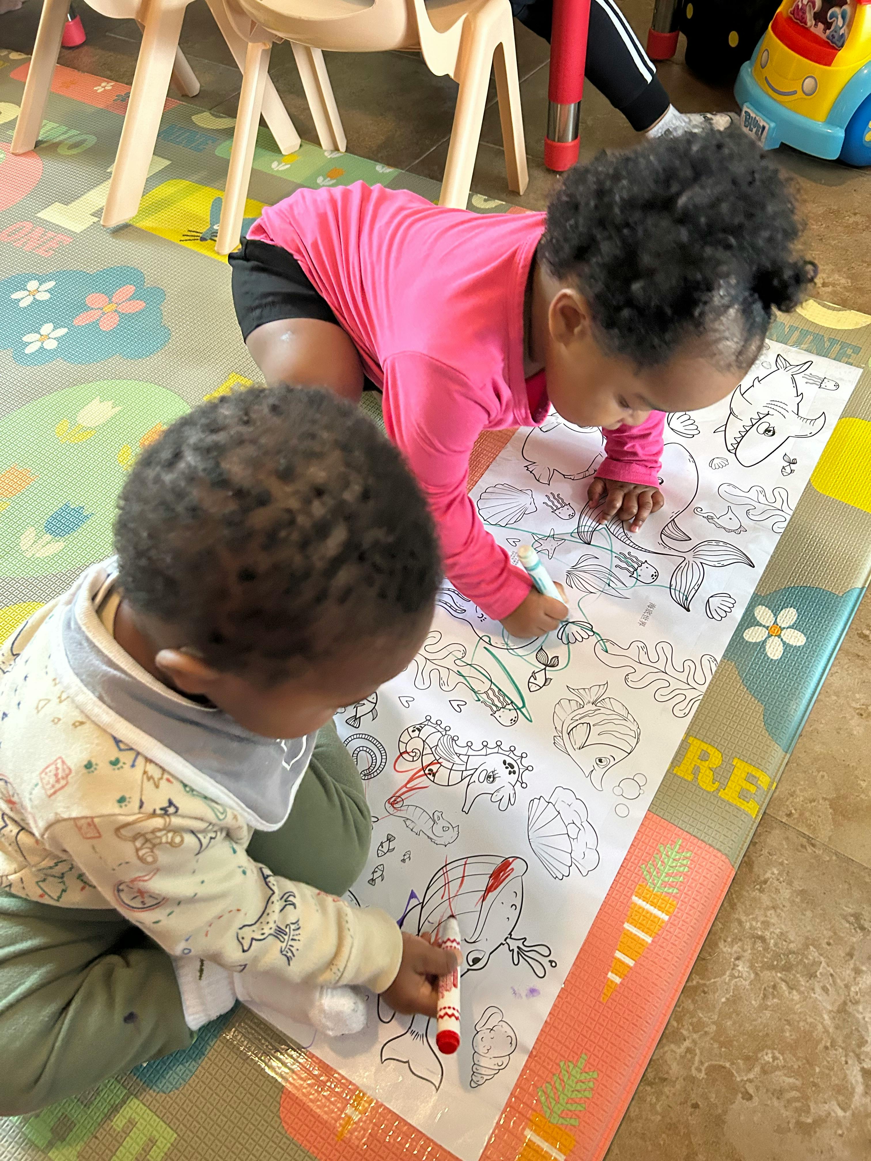 Two children coloring on a large paper