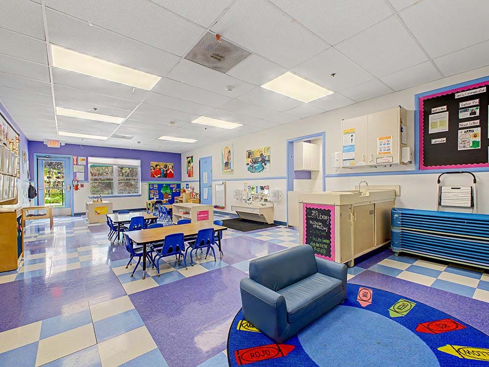 Classroom with small tables and chairs, a blue sofa, and a changing station