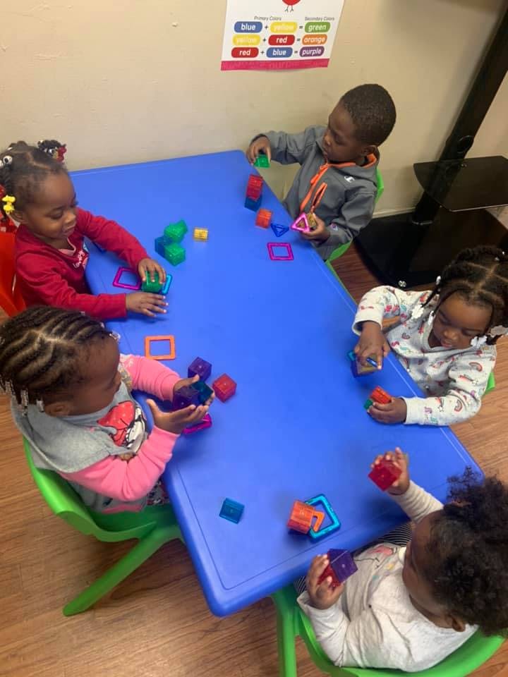 Four children playing with colorful blocks at a blue table