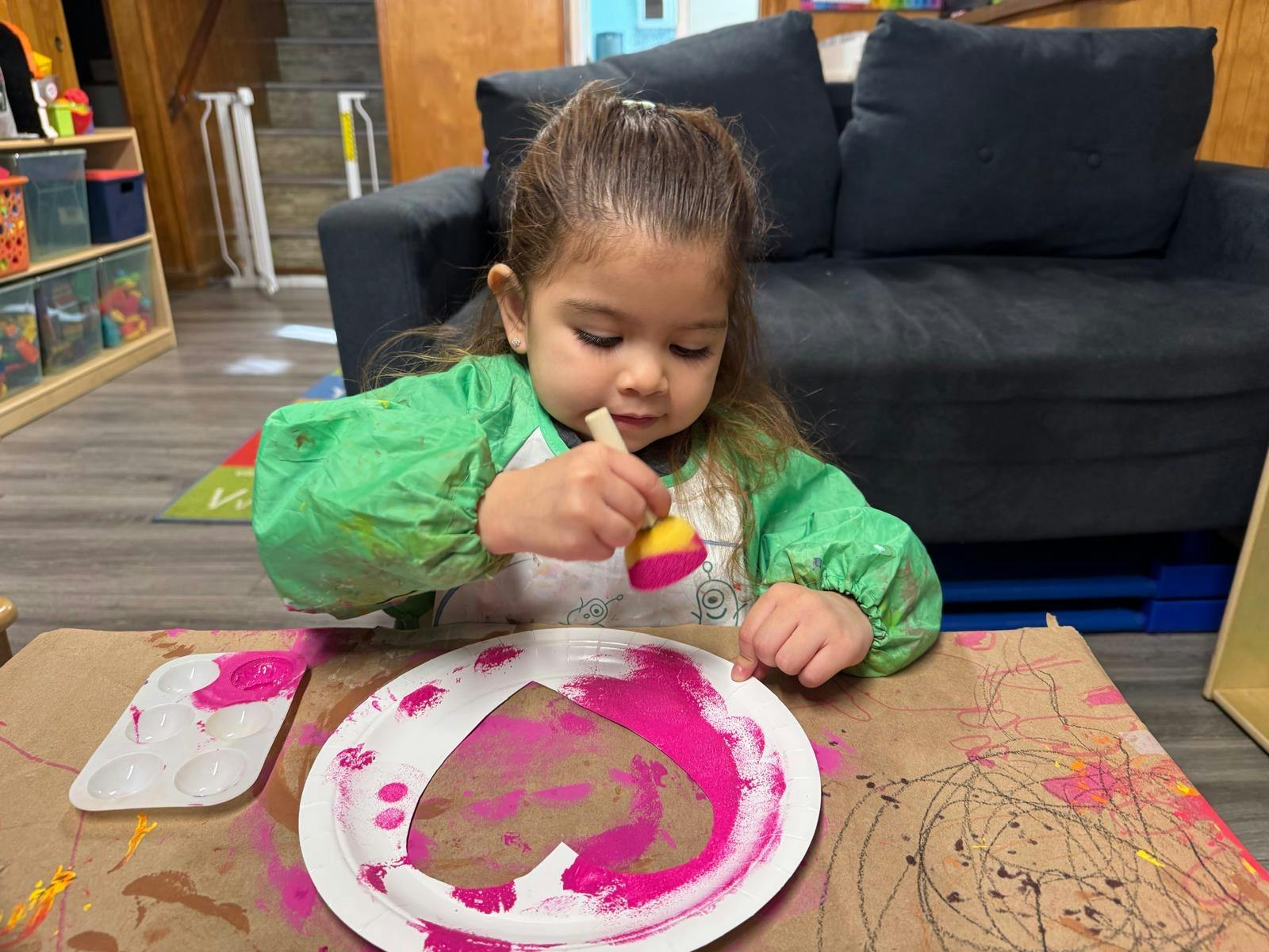 Child painting a heart shape on a paper plate
