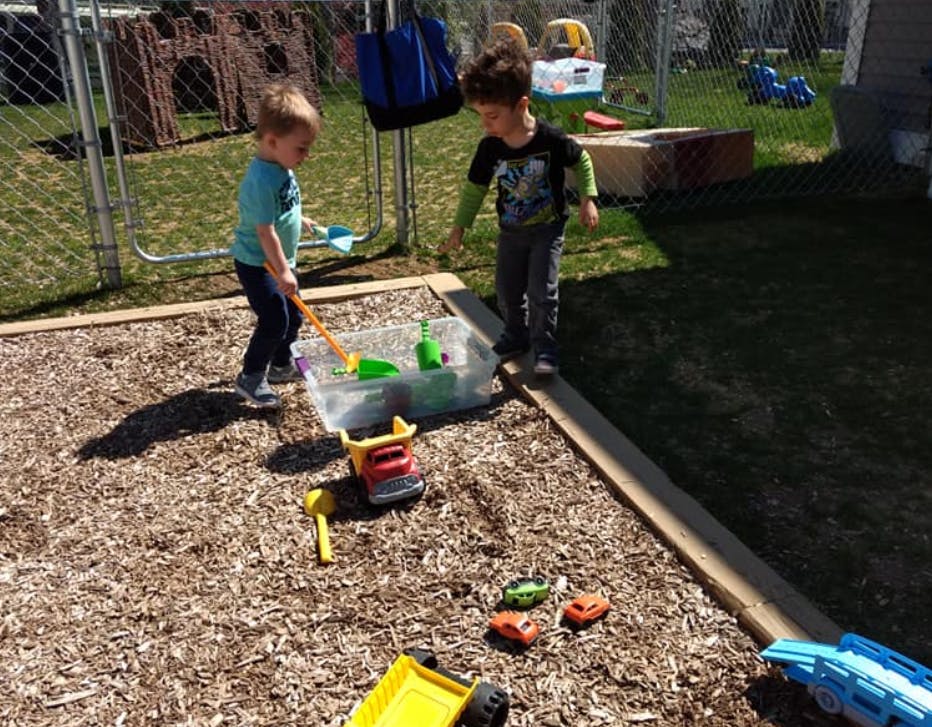 Two children playing with toys in a sandbox