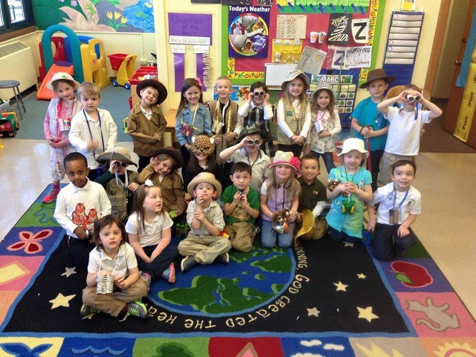 Group of children in a classroom, some wearing hats